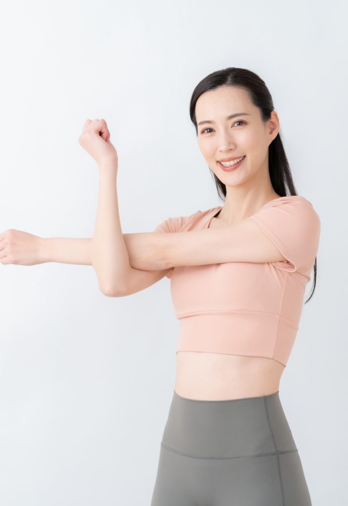 笑顔で腕のストレッチをする女性