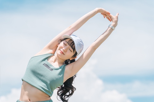 両手をあげて伸びをする女性