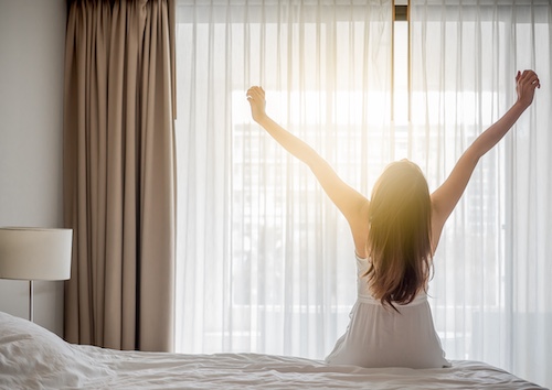 日光の当たる暖かい部屋で起床する女性